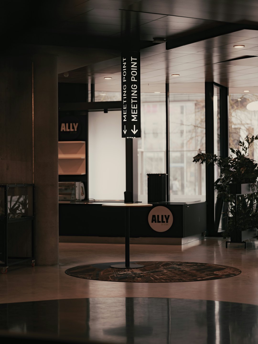 Modern lobby with 'MEETING POINT' sign and 'ALLY' branding.